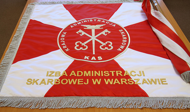 Sztandar Izby Administracji Skarbowej w Warszawie. Sztandar ma biało-czerwone kolory i godło: dwa skrzyżowane klucze na tle laski z uskrzydlonym kapeluszem Merkurego, na emblemacie w kształcie koła. Pod spodem napis z nazwą Izby.