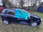 Samochód osobowy Fiat Grande Punto, samochód w kolorze granatowym, wybita szyba pasażera z przodu, wgniecione drzwi oraz uszkodzone lusterko